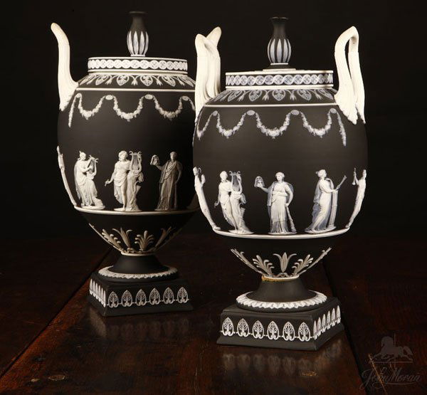 Near-pair Wedgwood black & white jasperware vases: 1952, marked 'Wedgwood / Made in / England'', each circular cover with baluster finial, over a tapering oval body with elongated handles, decorated overall with classical figures, above a circular foo