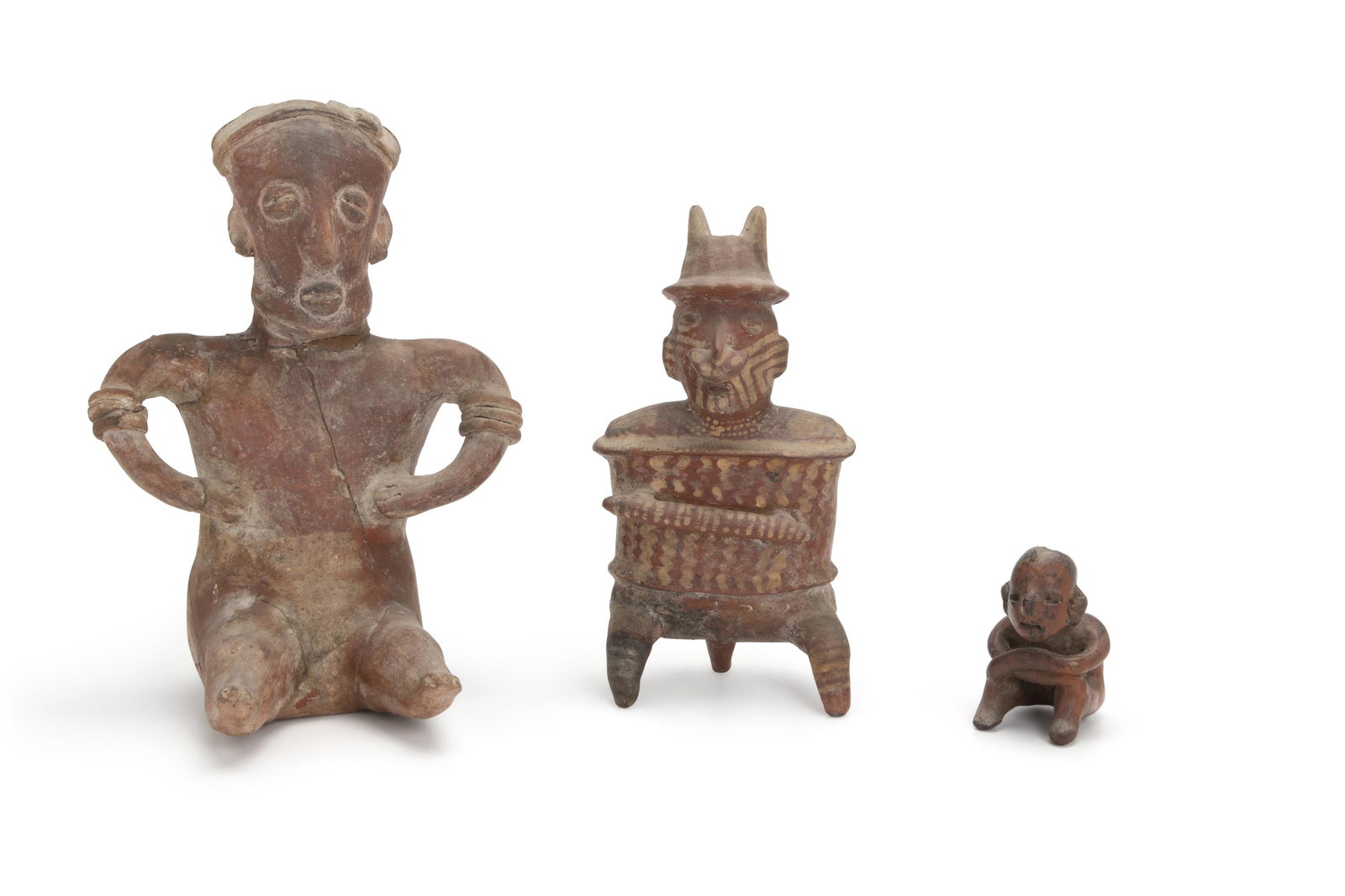 Three Pre-Columbian terracotta figures: 100 BCE-500 CE; Colima (Mexico) Comprising three seated figures, one warrior with pointed hat, nose ornaments, and painted necklace wearing armor, each with traces of various ancient polychrome pigmen
