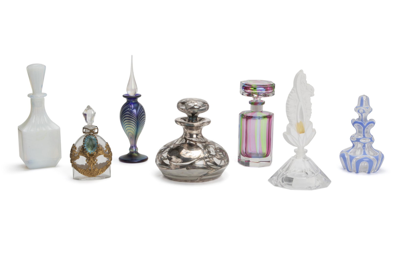 Seven perfume bottles: First-half 20th Century One initialed and numbered indistinctly to base Various styles including one opaline blue and purple, one squat form with silver overlay, and one multicolored striped glass,