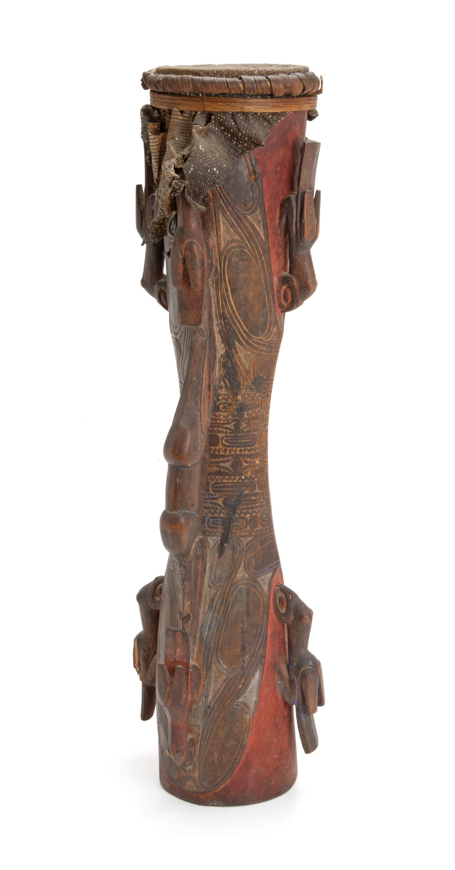 An Oceanic drum: Circa 1920-1930; Sepik River, Papua New Guinea The drum carved from a single piece of tropic hardwood in classic hour-glass shape with center side handle, both ends with carved bird and crocodile mot