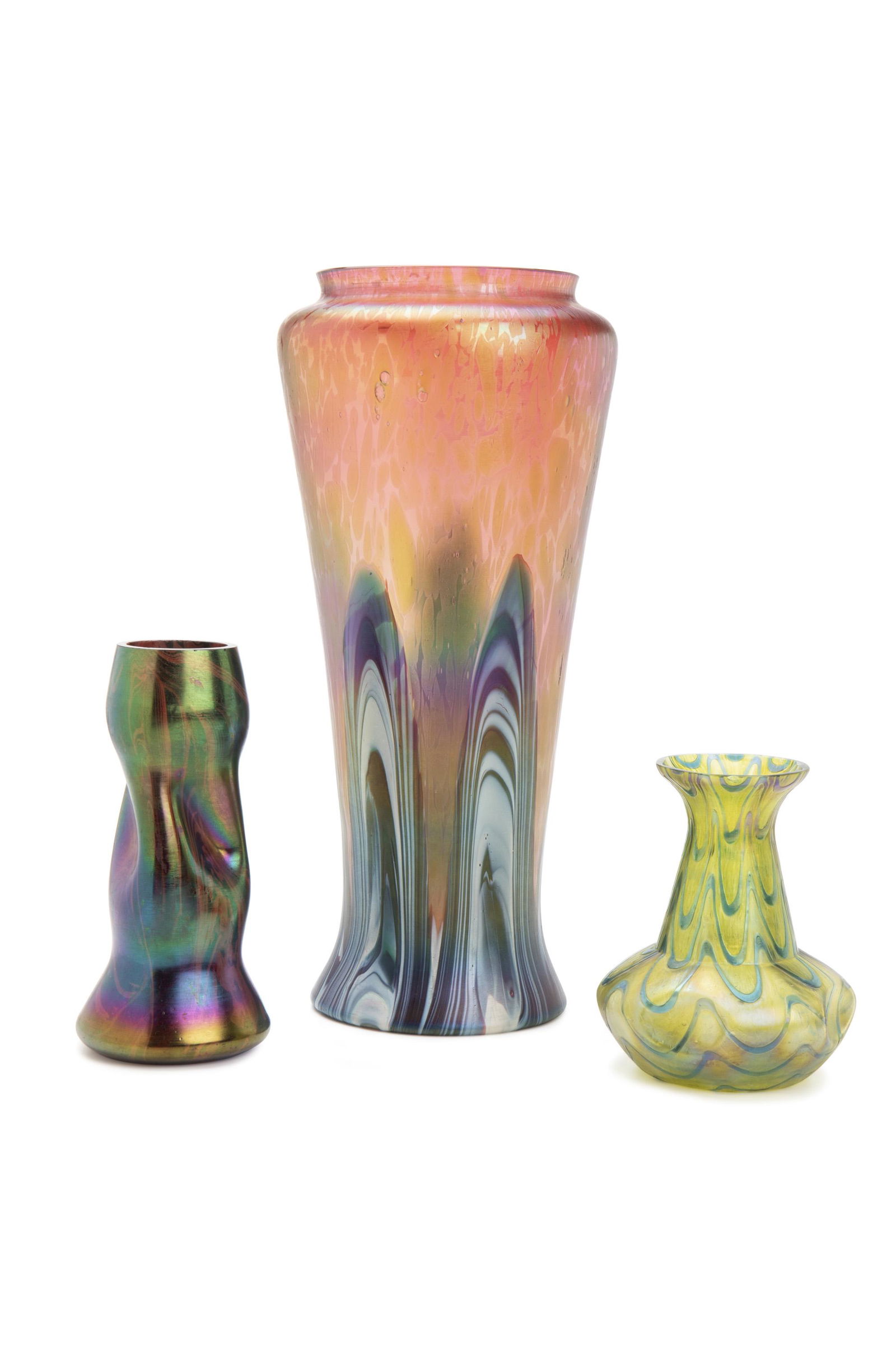 Three Loetz iridescent glass vases: Late 19th/early 20th Century; Bohemia (Czech Republic) Comprising three Art Nouveau glass vases in varying forms, one tall pink and blue iridescent vase, one narrow molded vase in purple and green gl