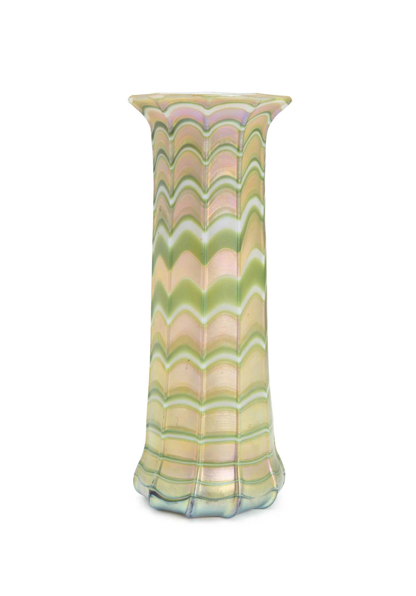 A Loetz-style iridescent glass vase: Late 19th/early 20th Century The green and gold iridescent vase with wide rim 8.75" H x 3.5" Dia.