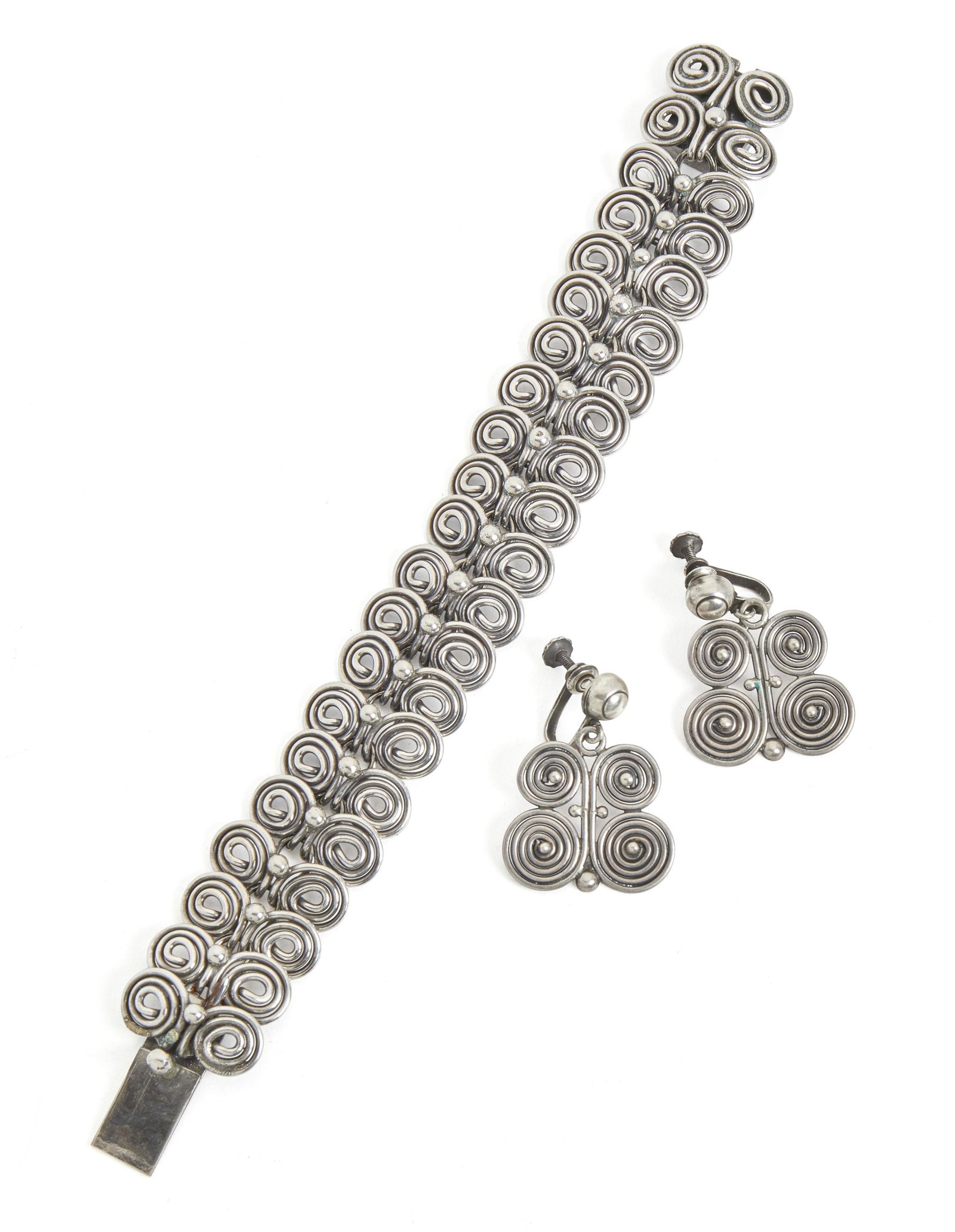 An assembled set of William Spratling silver jewelry: 1940-1944; First Design Period; Taxco, Mexico Each stamped for William Spratling; Further stamped: Made in Mexico / Silver Each designed with a tight curl motif, comprising a bracelet (7.325" L x 1" H