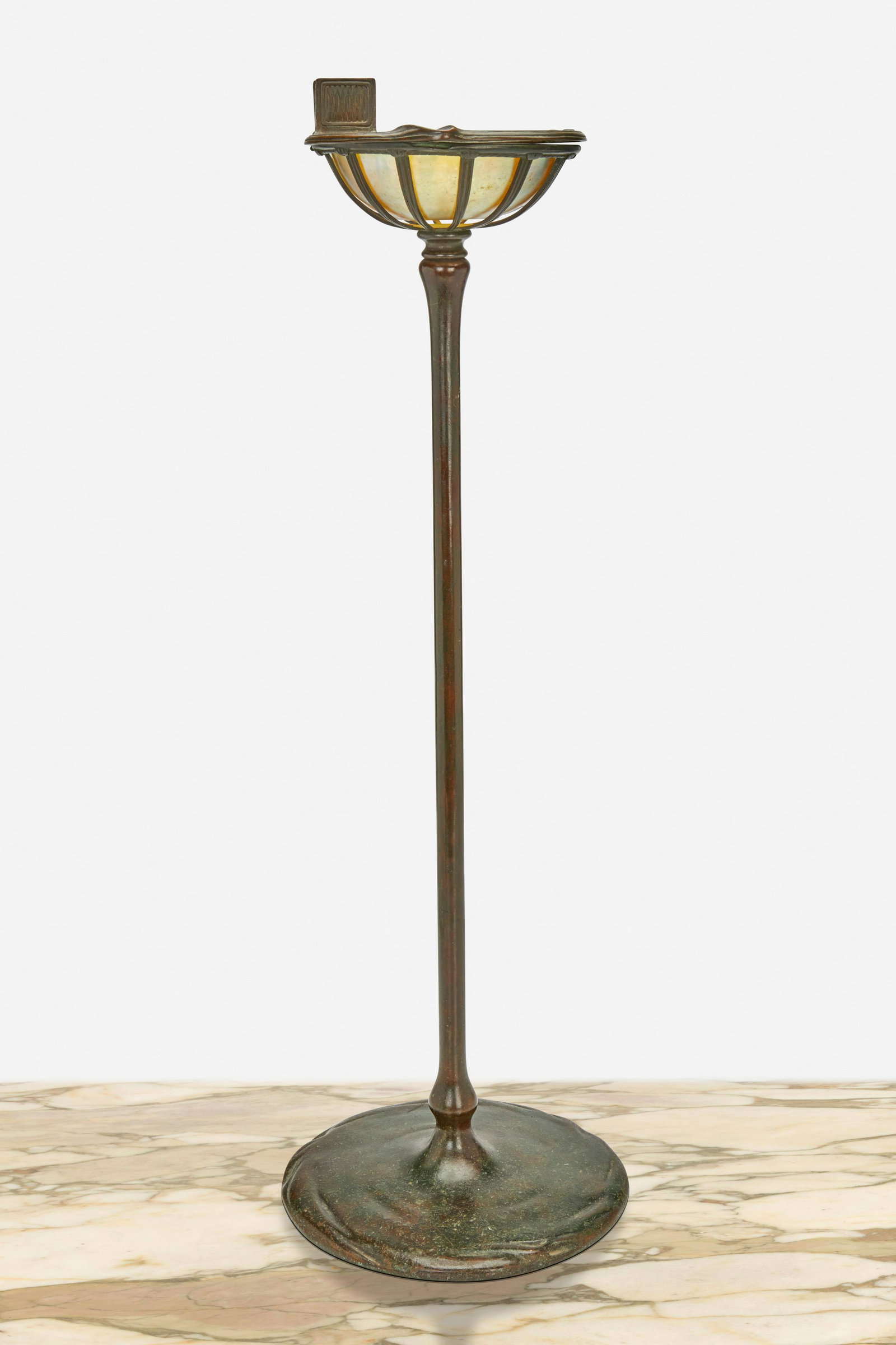A Tiffany Studios smoker's stand: Circa 1902-1919; New York, NY Base signed: Tiffany Studios / New York / 1649; Glass signed: L.C.T. / Favrile The patinated bronze smoker's stand with gold iridescent Favrile glass insert enclosed in a