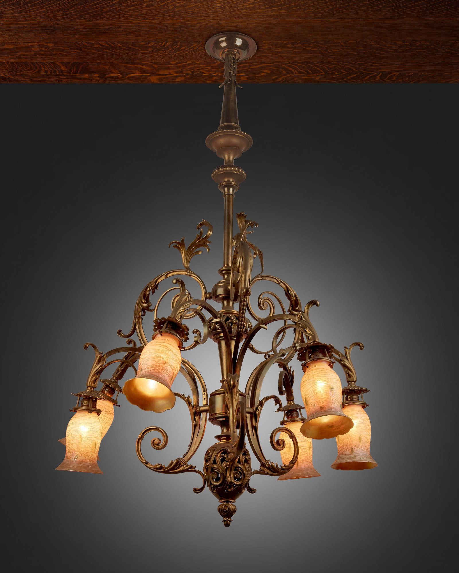 A Rococo-style gilt-bronze chandelier with Quezal art: First-quarter 20th Century Each shade signed: Quezal The six-light gilt-bronze chandelier with central knopped column, gadrooned canopy, openwork fonts, pointed finial, and scrolling foliage issuing s
