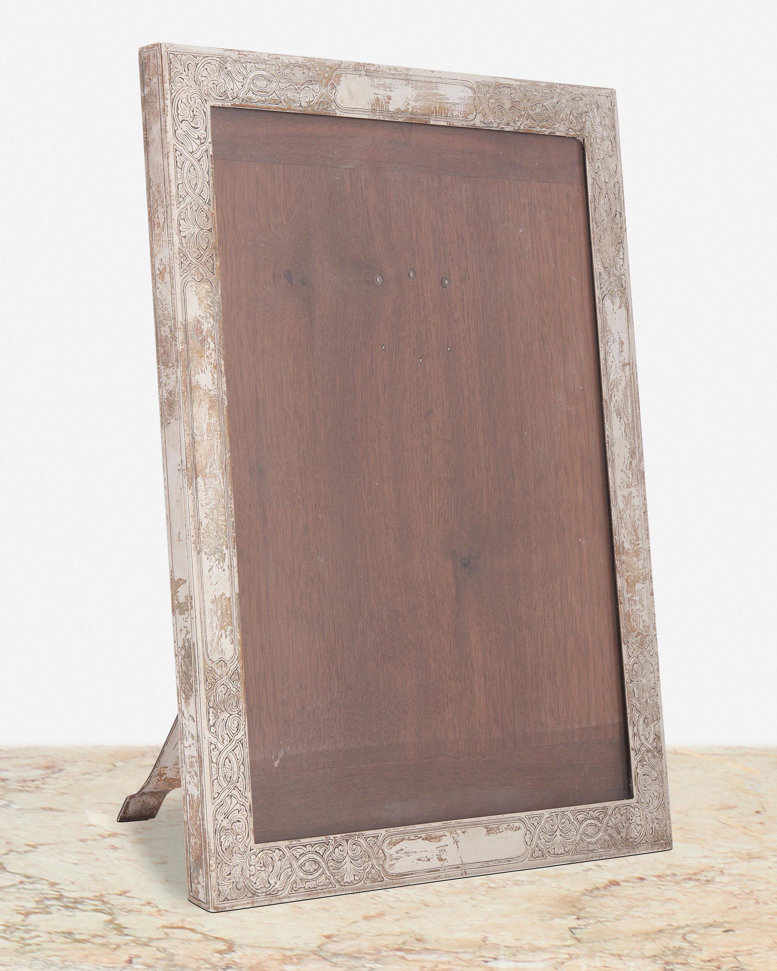 A Tiffany & Co. sterling silver picture frame: 1907-1947, directorship of John C. Moore II Marked: Tiffany & Co. / 16546Z Makers 13440 / Sterling Silver / 925-1000 / M The sterling silver easel back picture frame with scrolling foliate motifs and 
