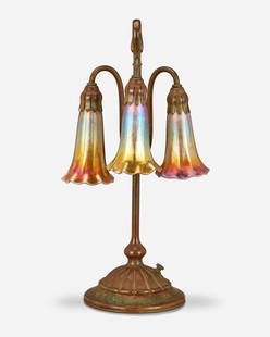 A Tiffany Studios three-light lily table lamp: Circa 1902-1919; New York, NY Each shade signed: L.C.T. / Favrile; Base signed: Tiffany Studios / New York / 306 The verdigris patinated bronze base with a domed ribbed foot and slender stem