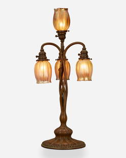 A Tiffany Studios patinated bronze table lamp: Circa 1899-1900; New York, NY Each shade signed: L.C.T.; Base signed: Tiffany Studios / New York / S 1129 / 1 The patinated bronze table lamp with an intertwined vine-style base with a pinched