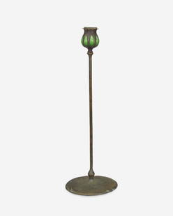 A L.C. Tiffany bronze and blown glass candlestick: Circa 1900-1902; New York, NY Signed: Tiffany Studios / New York / [T.G.D.Co. monogram] / 25956 The candlestick with a green blown Favrile glass capital with removable bobeche raised on a