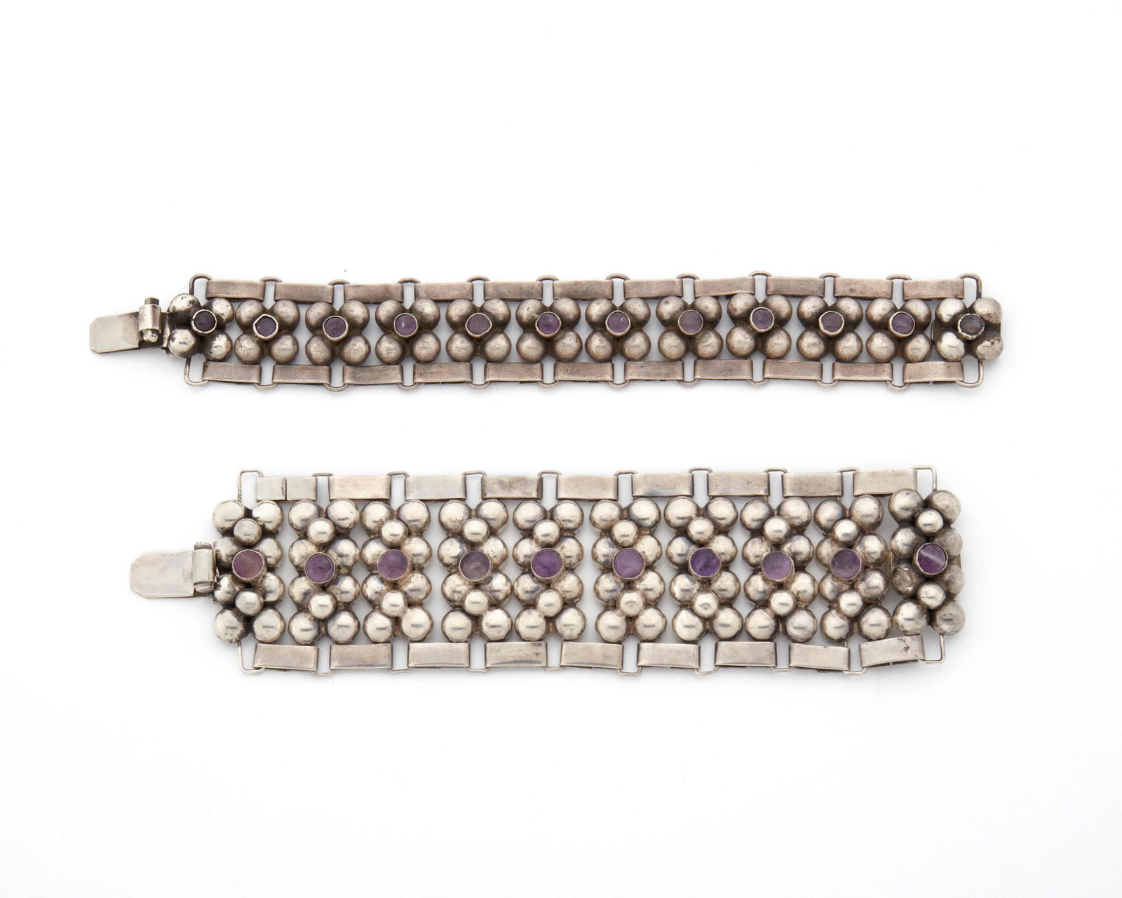 Two Fred Davis silver and amethyst bracelets: Pre-1948; Mexico City, Mexico Stamped: FD [Fred Davis]; Further stamped: Silver / Mexico The wide link bracelets comprising of rectangular clusters of silver half spheres each centering a round cabo