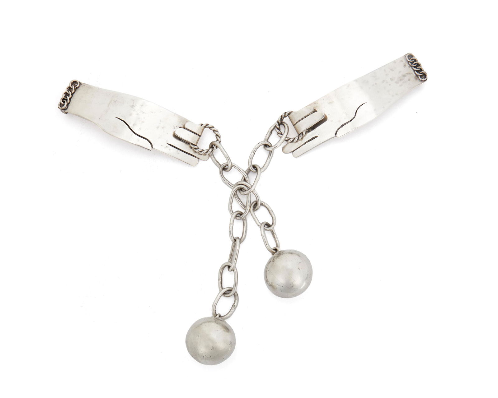 A Hubert Harmon silver and metal belt: Circa 1944-1948; Taxco, Mexico Stamped for Hubert Harmon; Further stamped: Sterling / Made in Mexico Designed as two hands pulling a silver chain suspending two metal spheres 11" W x 6" H Provena