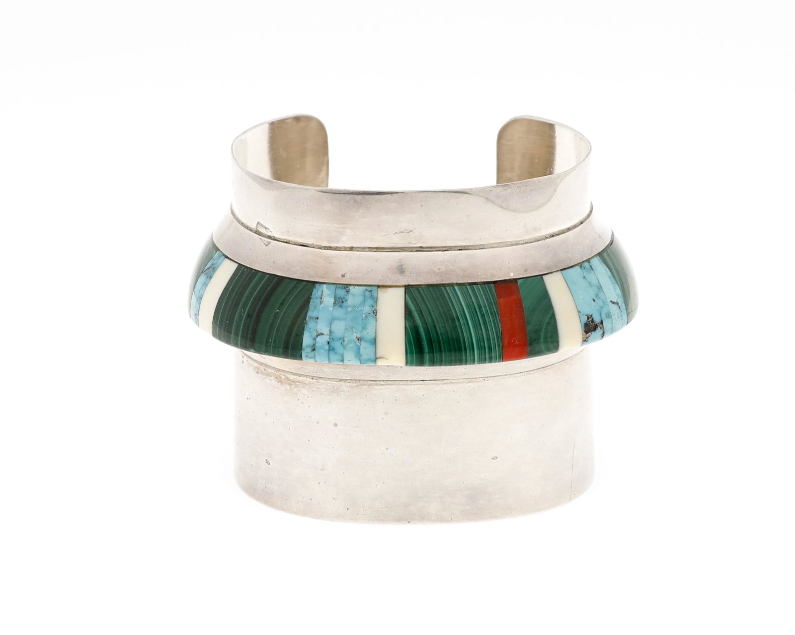 A Cleve Honyaktewa Hopi stone-set cuff: Fourhth-Quarter 20th Century Marked with conjoined CH Comprising a modern style cuff with raised inlay including malachite, turquoise, and coral 6.25" total inner C x 2.25" H, wrist opening: 1.125" 11