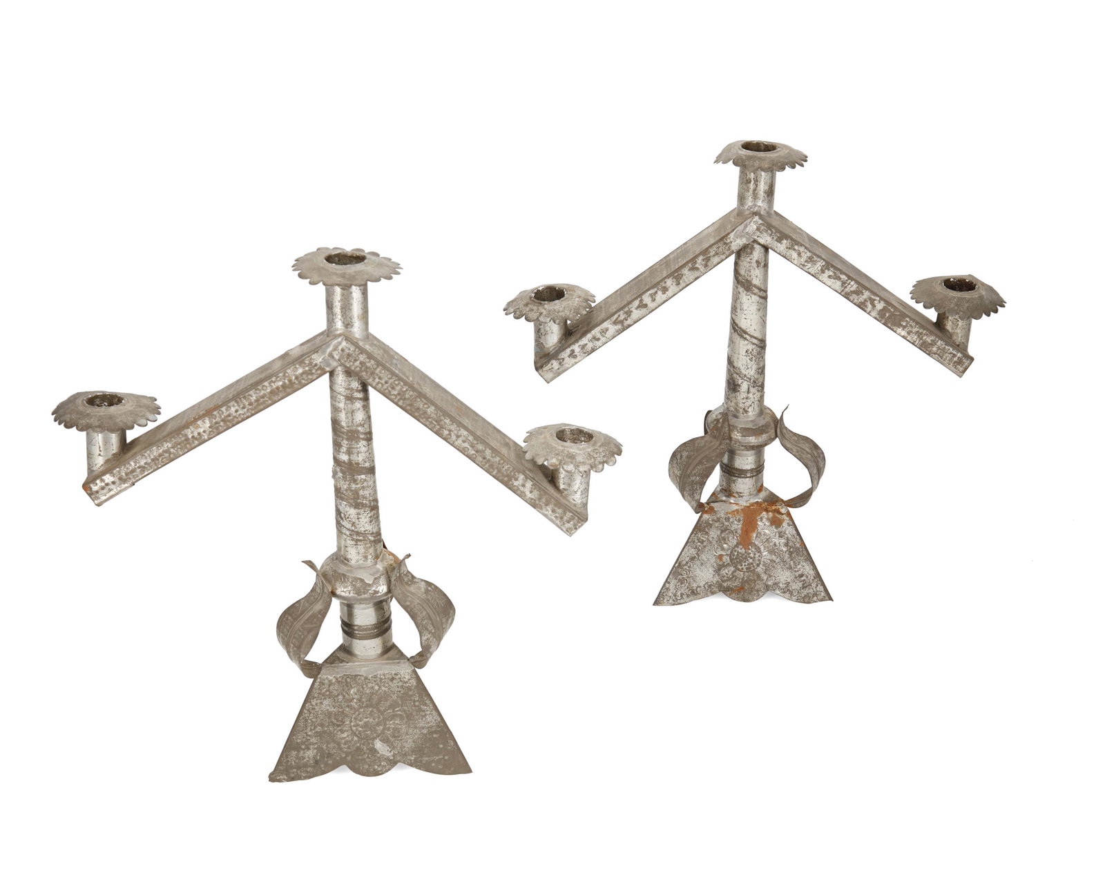 A pair of sand-weighted tin candelabra: Circa 1940s; Mexico Each three-light candelabrum with floral and leaf motifs and chased designs, 2 pieces Each: 13.25" H x 13" W x 4.75" D