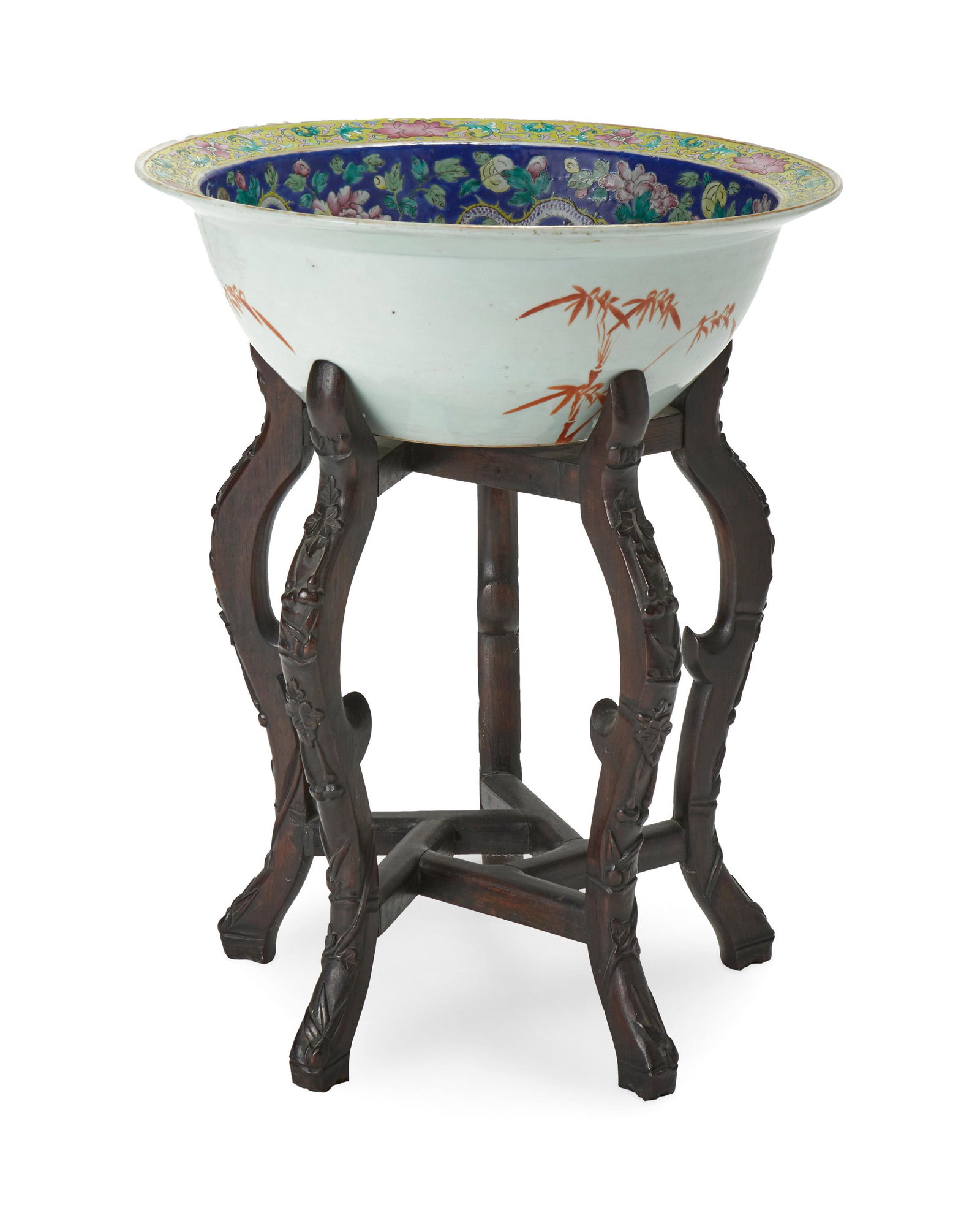 A Chinese porcelain bowl: 20th Century Stamped to the underside: China The glazed porcelain bowl painted in hues of blue and yellow with flowers and dragons, on a wood stand Bowl: 6.25" H x 18" Dia.; On stand: 23.5" H