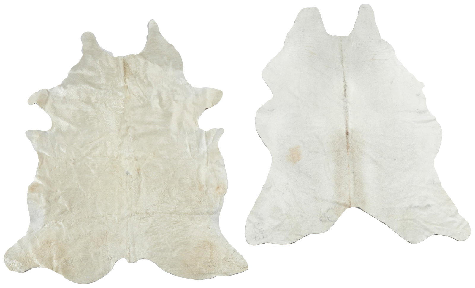 A pair of cowhide rugs: 21st Century One with stamped label underside: [illegible] / Made in Brazil; One with various markings and labels to underside Each with white fur and natural edge, 2 pieces Larger: 89" L x 75" W; Sma