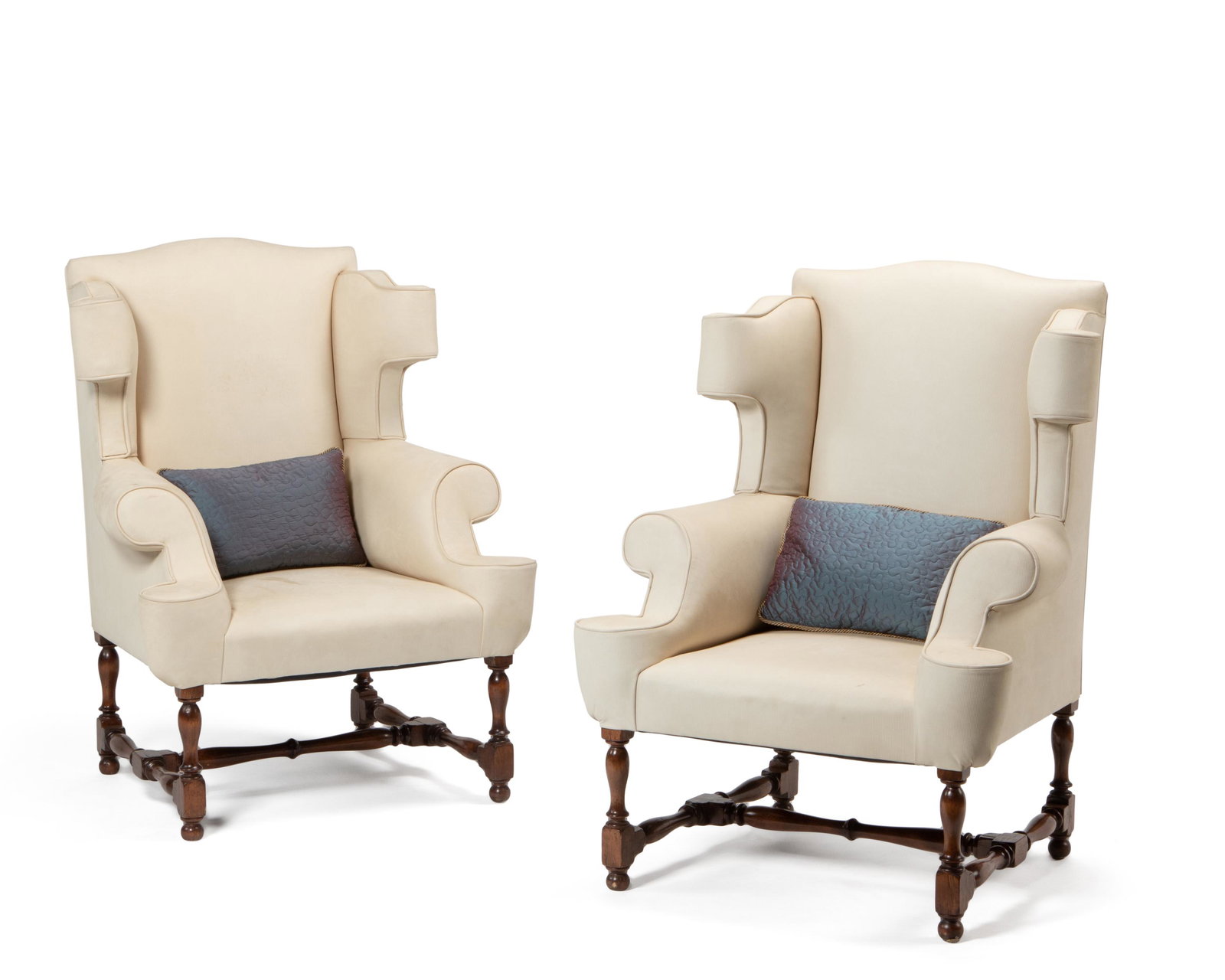 A pair of wingback armchairs: 20th Century Each chair with stylized wings and arms upholstered in cream pinstripe microfiber fabric on walnut-toned turned wood feet and stretcher, together with two blue taffeta pillows, 4 pieces E
