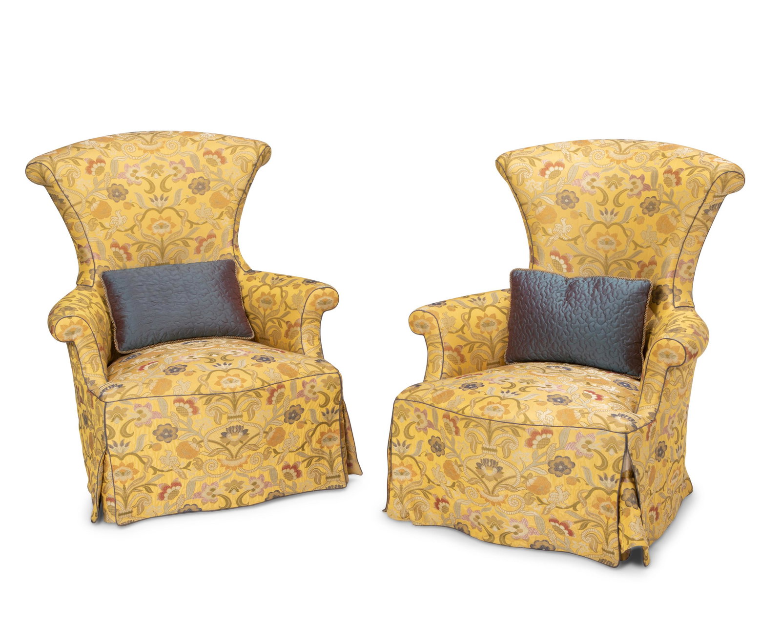 A pair of upholstered armchairs: Late 20th/Early 21st Century Each upholstered in Chintz-style fabric with multi-colored flowers on a mustard yellow ground and with blue piping, together with blue taffeta pillows, comprising two chai