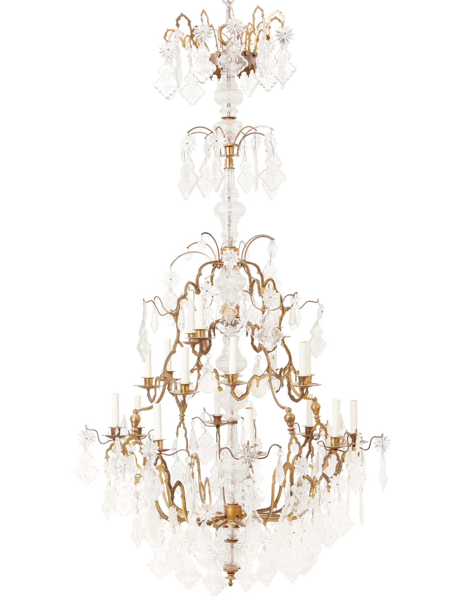 A bronze and crystal chandelier: 20th/21st Century The twenty-light chandelier with a tiered bronze frame with scrolled arms and cut crystal prisms, rosettes, and pendalogues with impressed angel masks, crucifixes, and "IHS," electri