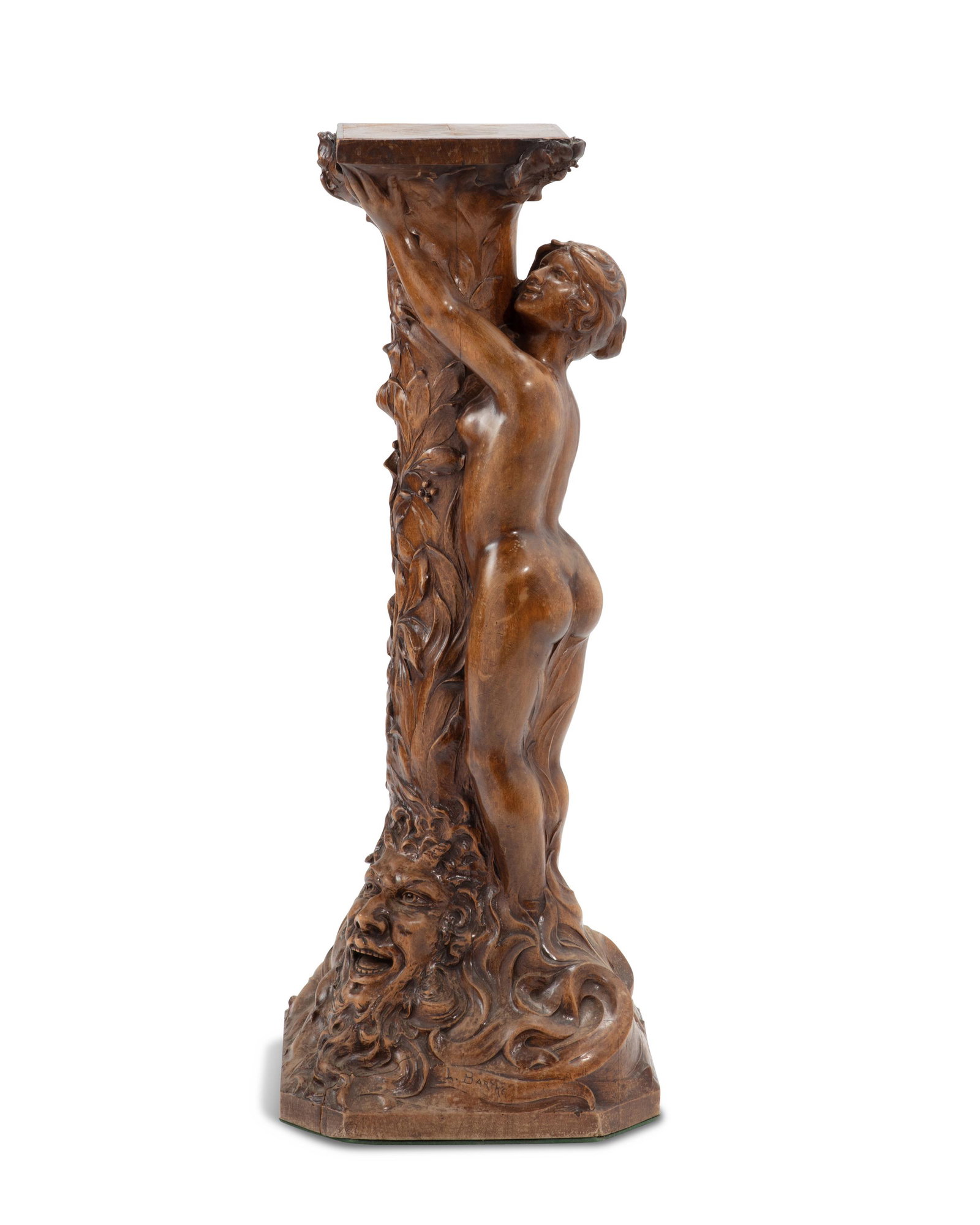 An Art Nouveau carved wood plant stand: Late 19th/Early 20th Century Signed L. Barthe The carved wood stand depicting a nude woman clinging to a column covered in flowering vines over a mask of a satyr 40.5" H x 16" W x 15" D