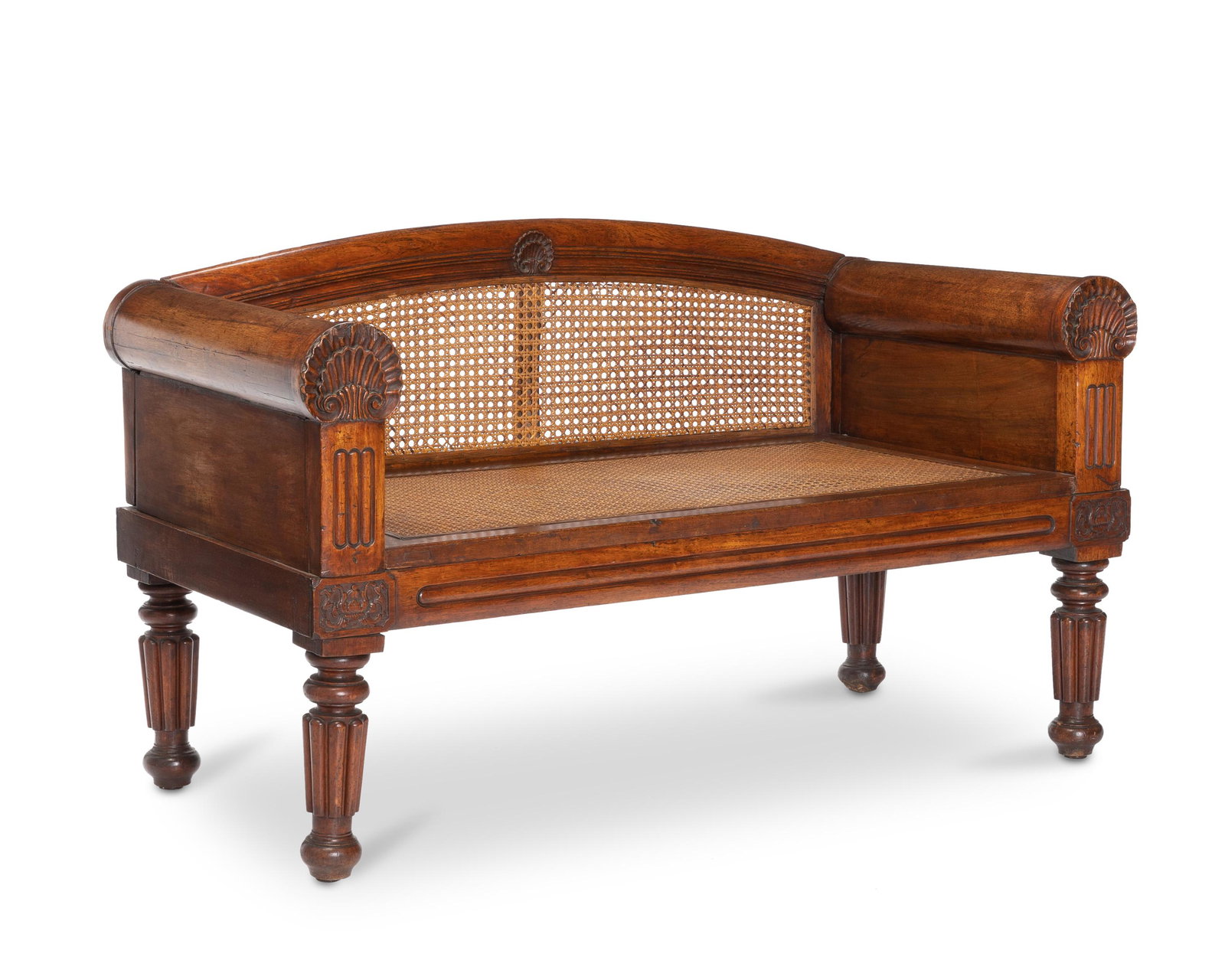An Anglo-Indian wooden bench: 20th century With carved wood with shell motif on the arms and apron; and woven cane seats and back 27" H x 51" W x 23.25" D
