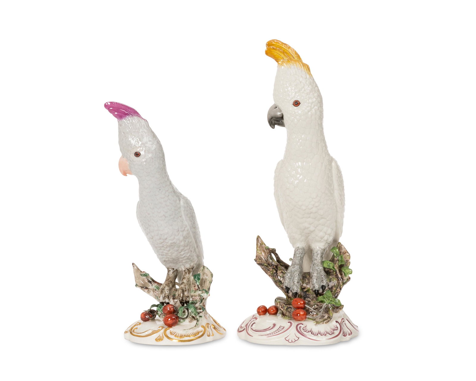 Two Nymphenburg porcelain cockatoo figures: Early 20th century Each marked with impressed Nymphenburg shield; one with green overglaze Nymphenburg mark Each glazed porcelain with gilt highlights perched on a branch with berries, 2 pieces Larger