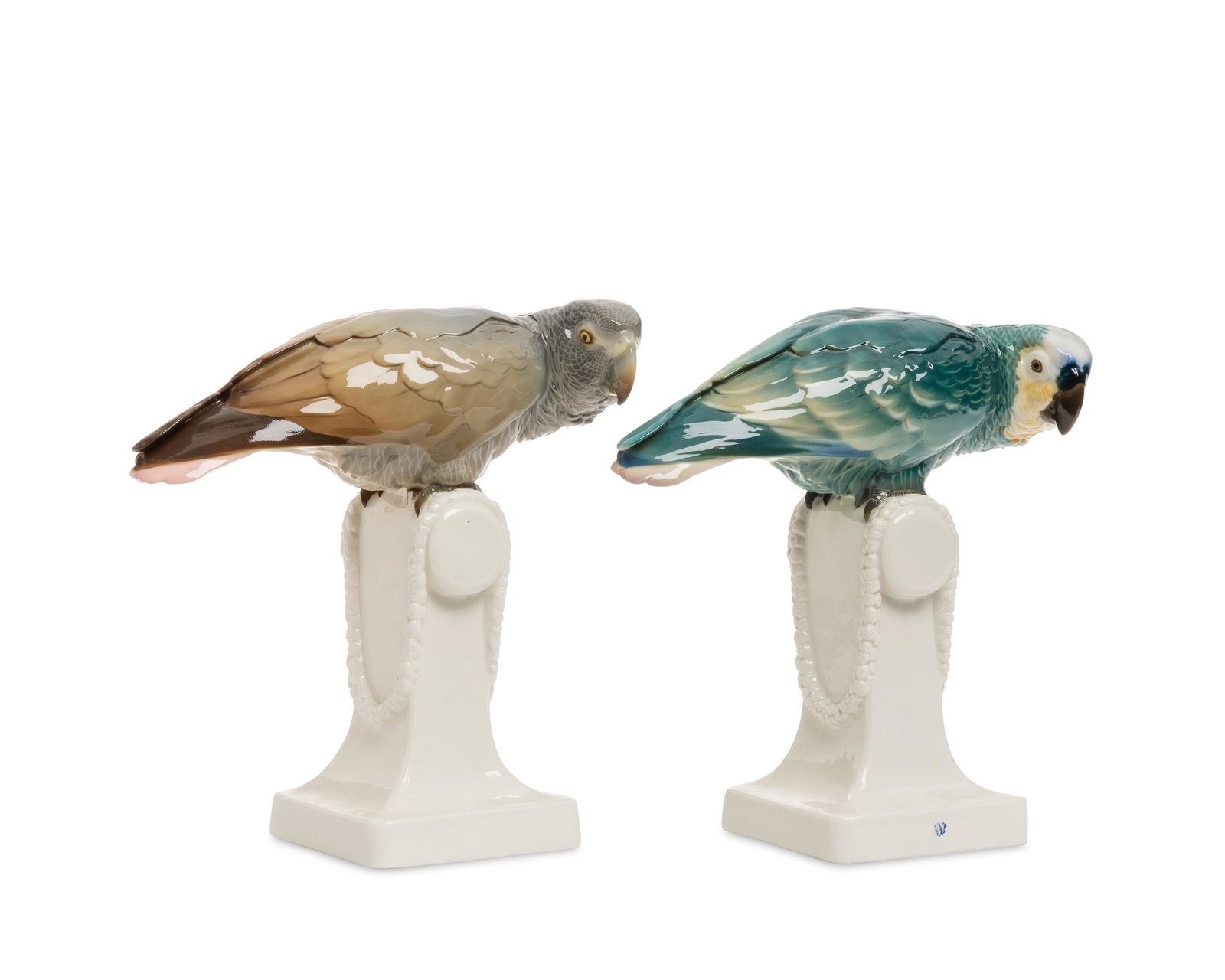 Two Nymphenburg porcelain parrot figures: Early 20th century Each marked with impressed Nymphenburg shield; grey parrot signed and dated: F.C. 1913; blue parrot signed with cipher Each glazed porcelain, comprising a blue and a grey parrot on 