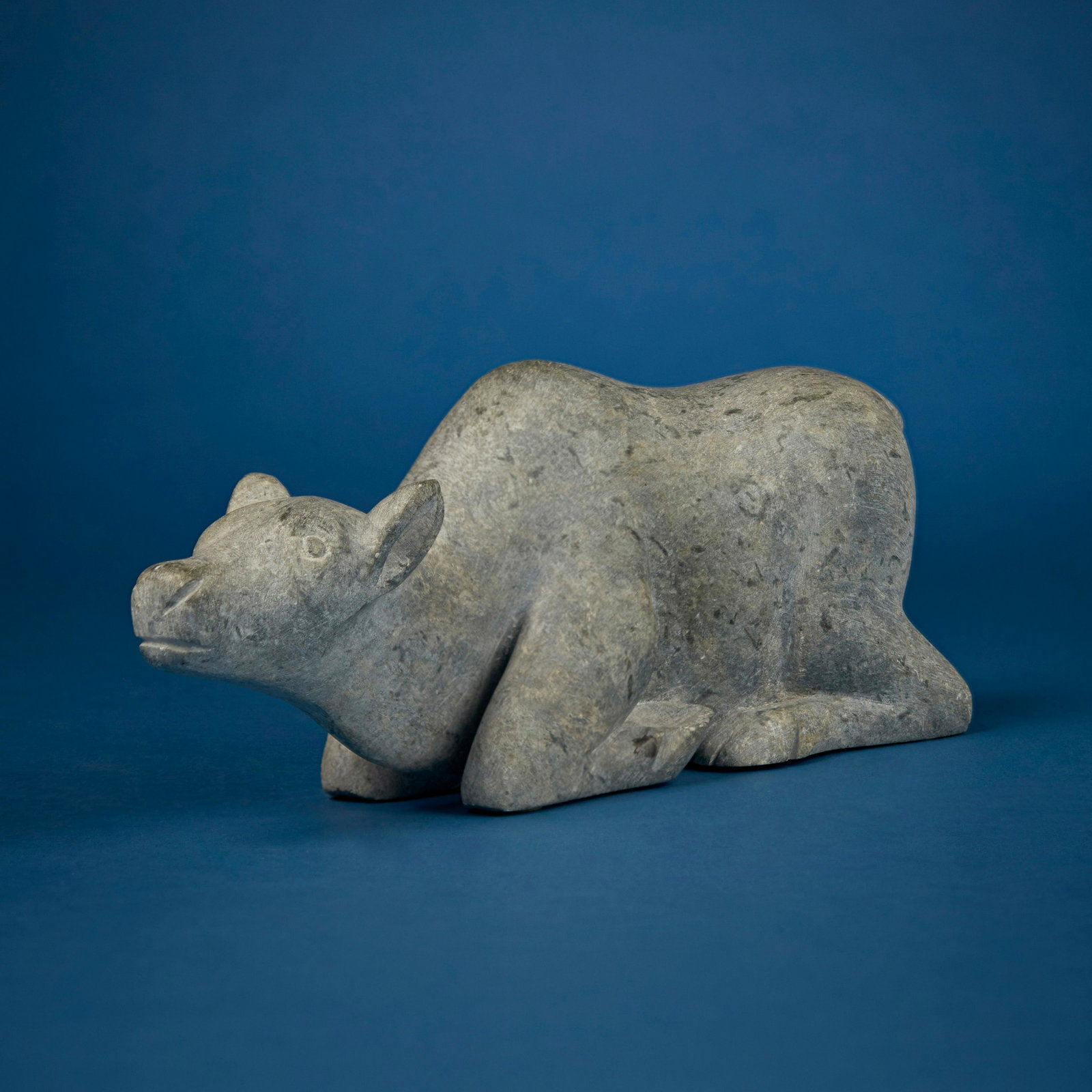 Annie Komek (Etokto) Kiguina (b. 1947, Inuit; Coppermine/Kugluktuk), Kneeling caribou, circa 1980: Annie Komek (Etokto) Kiguina (b. 1947, Inuit; Coppermine/Kugluktuk) Kneeling caribou, circa 1980 Stone Unsigned; marked with sticker to underside: Canada eskimo art 4' H x 11.25" W x 3" D Pr