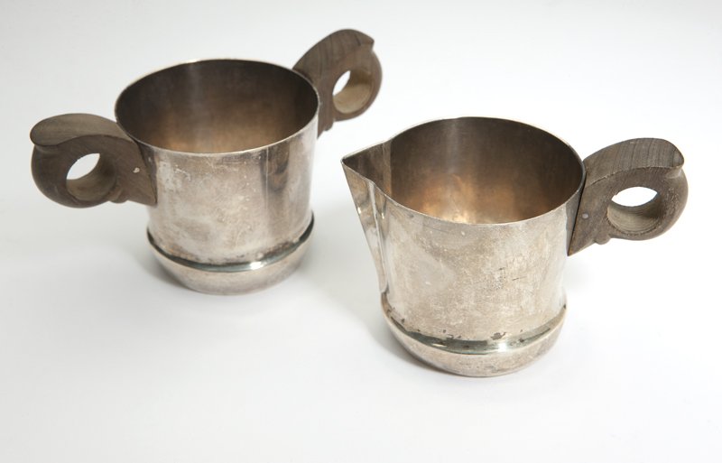 A Mexican sterling silver cream jug and sugar bow: 1931 - 1945, with maker's mark ''Spratling made in Mexico'' encircling conjoined ''WS'' and ''Sterling'', each of tapering circular form on bulbous bases, with hardwood handles, 2 pcs, 2.25'' H x 2.5'