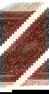 A Kork small area rug: A Kork small area rugEarly/mid-20th centuryThe diminutive, washed wool on silk rug with allover foliate motifs surrounding a central medallion on a burgundy ground5' 2" L x 3' 1" W
