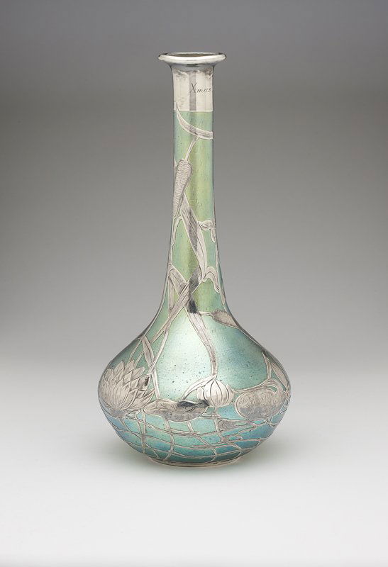 A sterling overlay iridescent green glass vase: Circa 1900, unsigned, possibly Loetz, inscribed to neck ''Xmas 1903'' and to body ''To Florence and Wick from Harold'', of bottle-form decorated with a swan afloat amongst cattails and waterlillies, 1