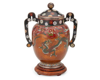 An East Asian cloisonnE vessel: An East Asian cloisonnE vessel20th centuryAppears unmarkedThe polychrome enamel and white metal alloy lidded vase with two opposed handles featuring dragons on an orange micaceous ground and phoenixes