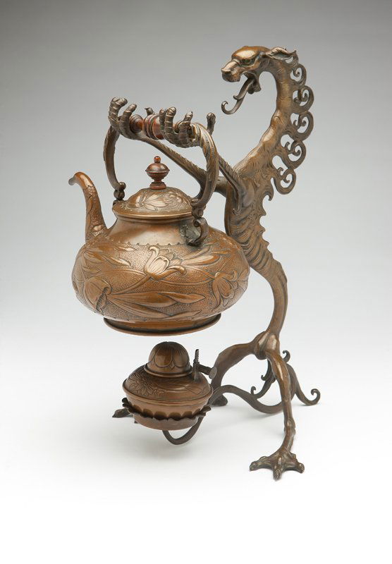 A bronze tea kettle on stand: Circa 1900, unmarked, in pseudo-Asian style of copper-washed bronze, the stand modeled as a dragon, his extended claws forming a support for the hanging repousse-decorated teapot, his tail supporting