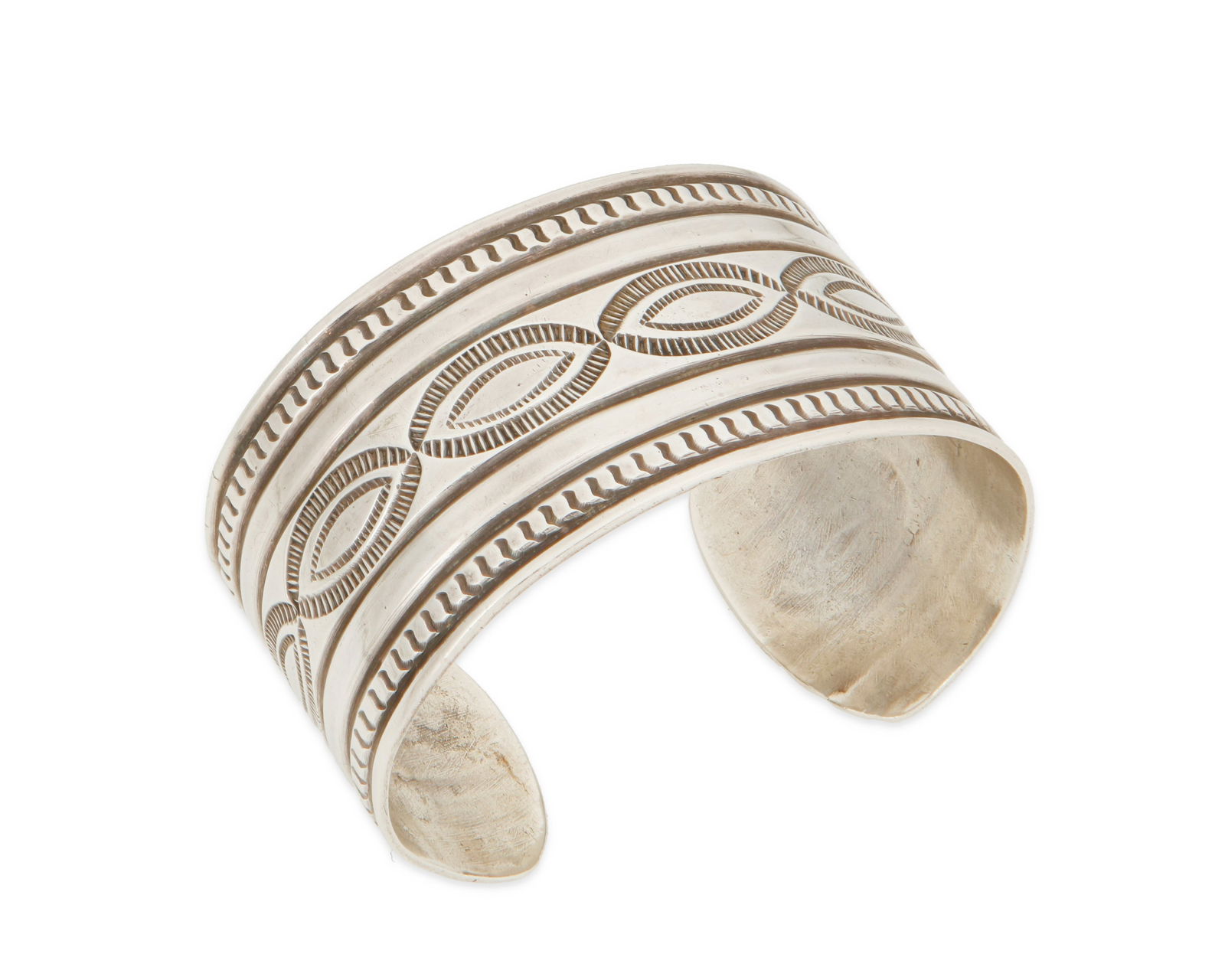 A Southwest sterling silver cuff bracelet: A Southwest sterling silver cuff bracelet20th centuryEtched verso: T U E [or TYE]An ingot silver cuff with stamped and chased motifs6.625" total inner C x 1.375" H, with a 1" gap49.7 gr