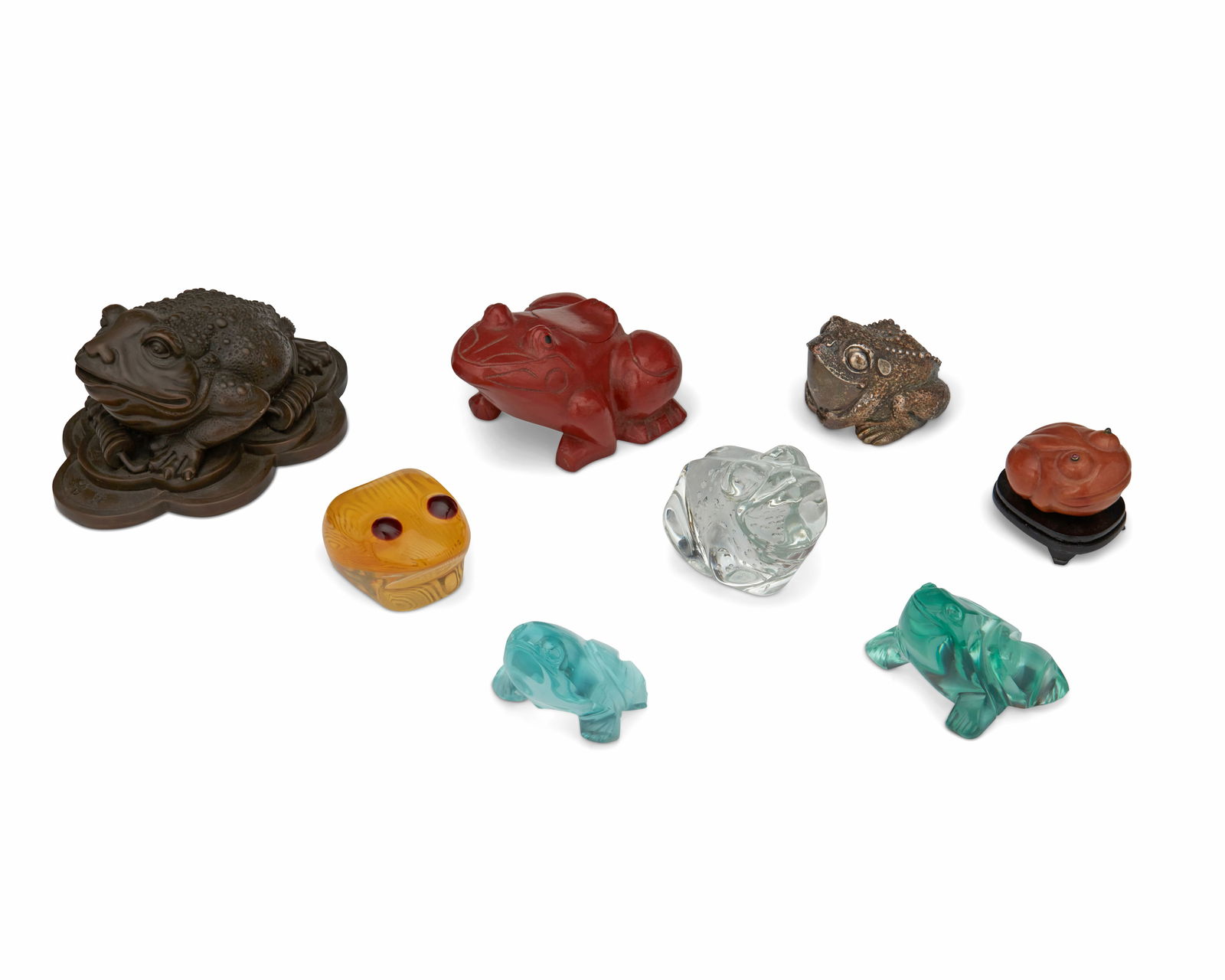 A group of frog figurines: A group of frog figurines20th centuryOne marked for sterlingEight frog figurines of various size and material comprising three glass frogs, one lacquered carved wood frog with a hinged lid and interio
