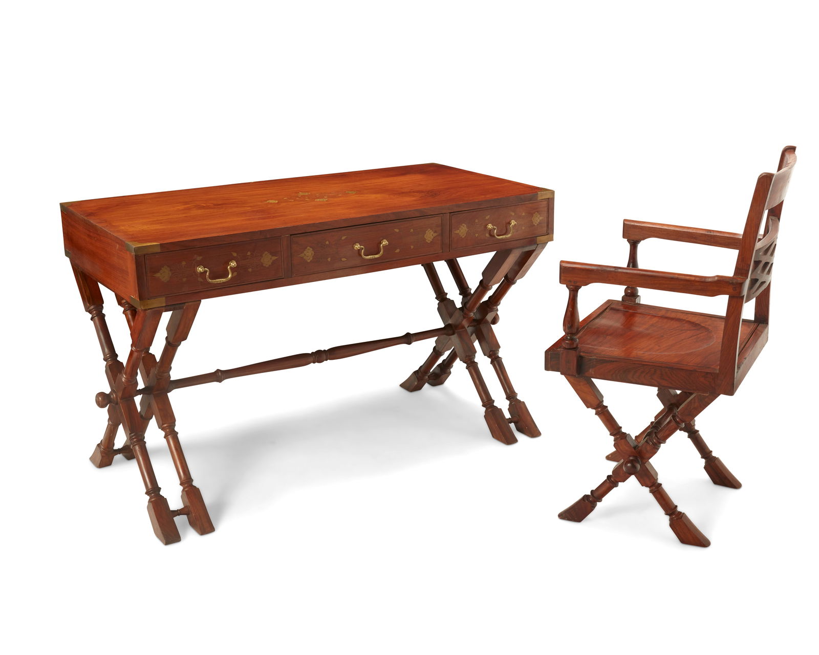An Anglo-Indian military desk and chair: An Anglo-Indian military desk and chair19th CenturyThe desk with three drawers raised on double X-form legs joined by a turned stretcher, featuring inlaid brass floral accents to drawer fronts, tablet