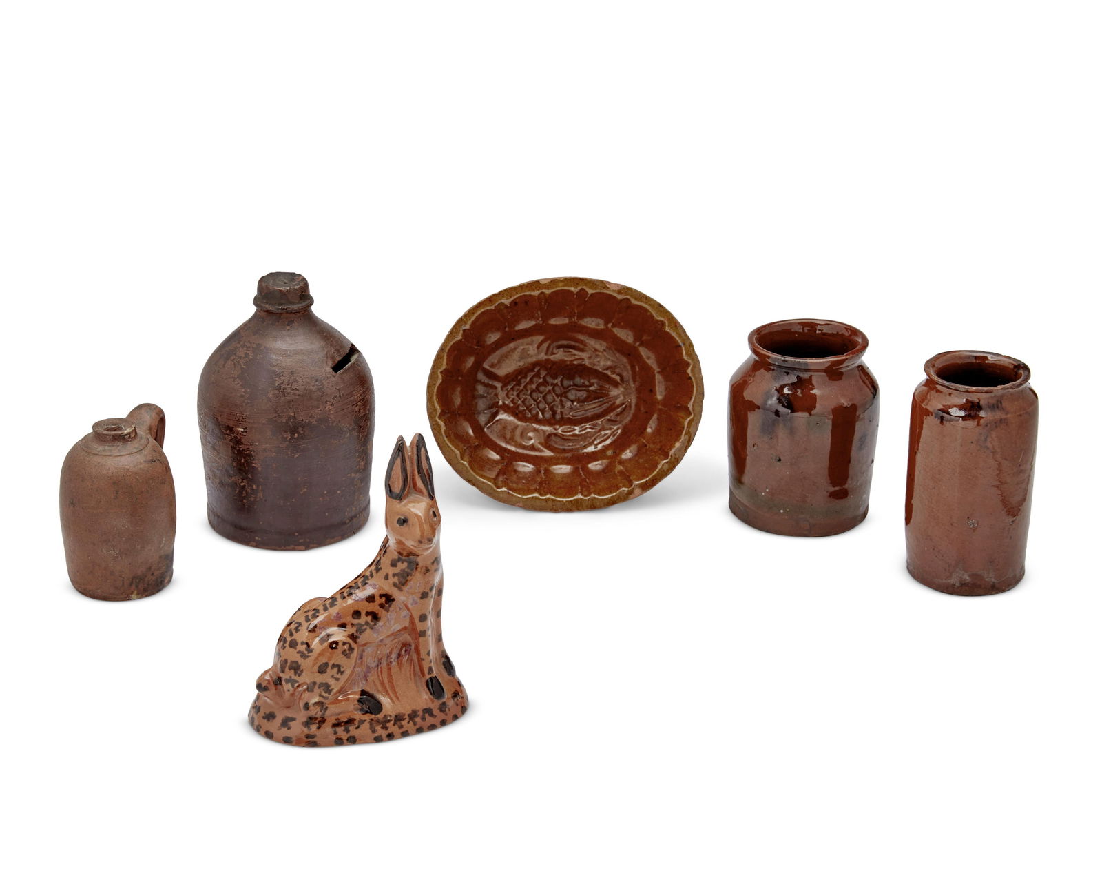 A group of Pennsylvania redware pottery items: A group of Pennsylvania redware pottery items18th/19th centuryEach unmarkedThe glazed earthenware group comprising a jelly mold, a piggy bank, a rabbit figure, two small crocks, and a small handled ju