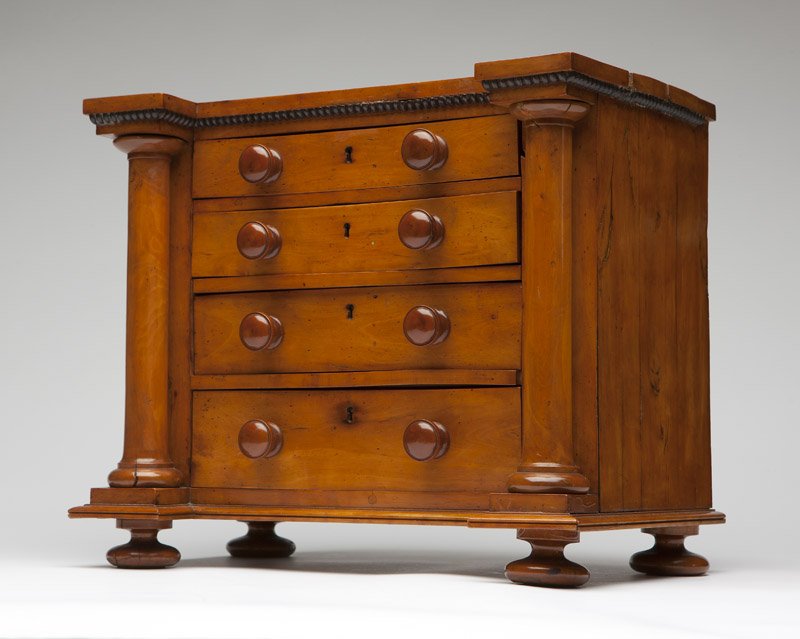 Biedermeier fruitwood miniature chest of drawers: Mid 19th century, the rectangular top with projecting front corners over an ebonized beaded molding above four graduated drawers flanked by engaged Doric columns raised on bun feet, 12'' H x 14.25'' W