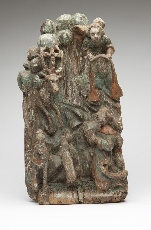A Northern European carved wood relief St Hubert: 16th - 18th century, polychrome painted, depicting in high relief the conversion of Saint Hubert whilst hunting in a forest accompanied by dogs and a horse, the saint wearing a hunting horn and kneeli