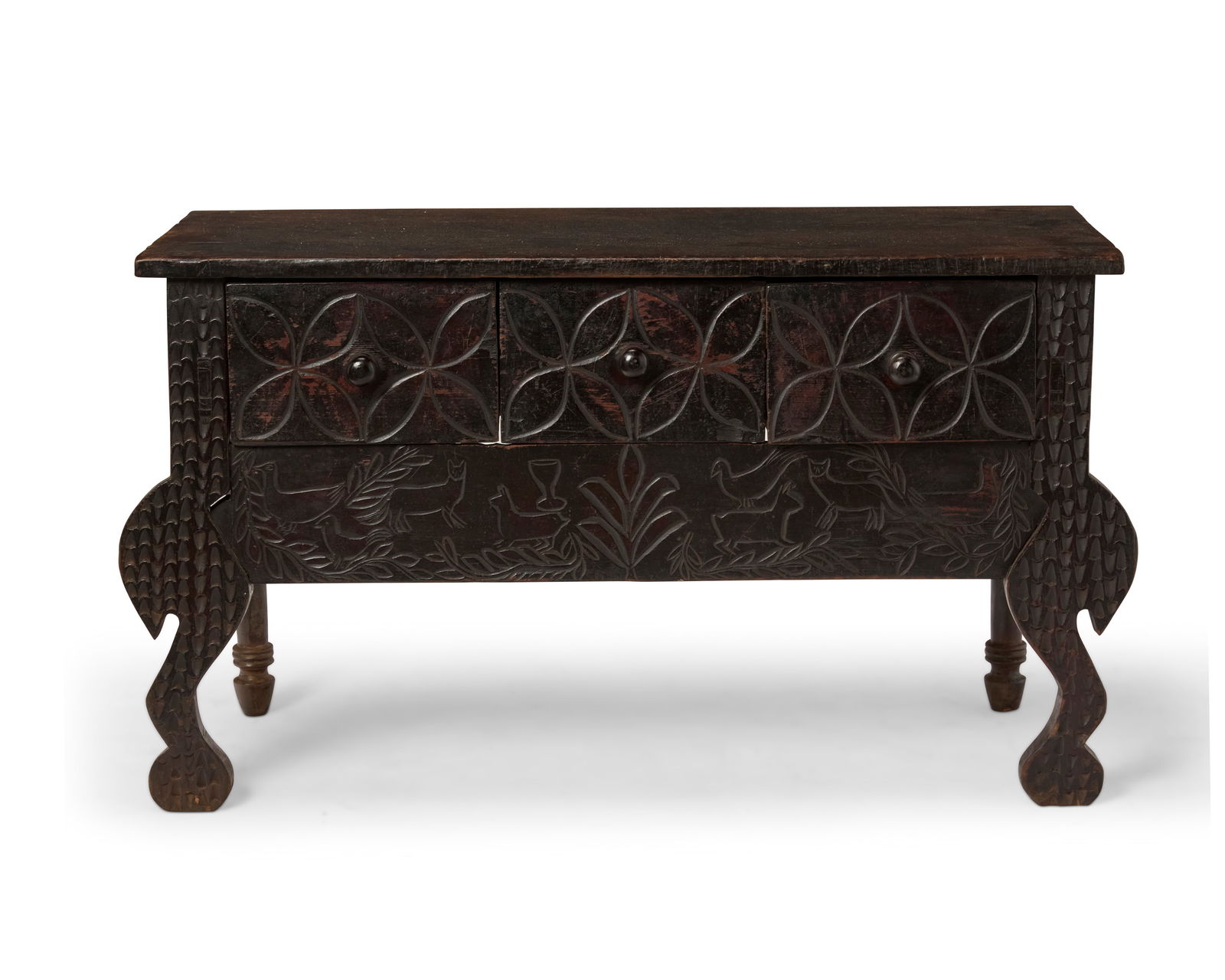 A Guatemalan Nahuala table: A Guatemalan Nahuala tableLate 19th/early 20th centuryThe carved wood table of mortise and tenon construction, with three drawers and anterior turned legs, the front featuring motifs of flora and faun
