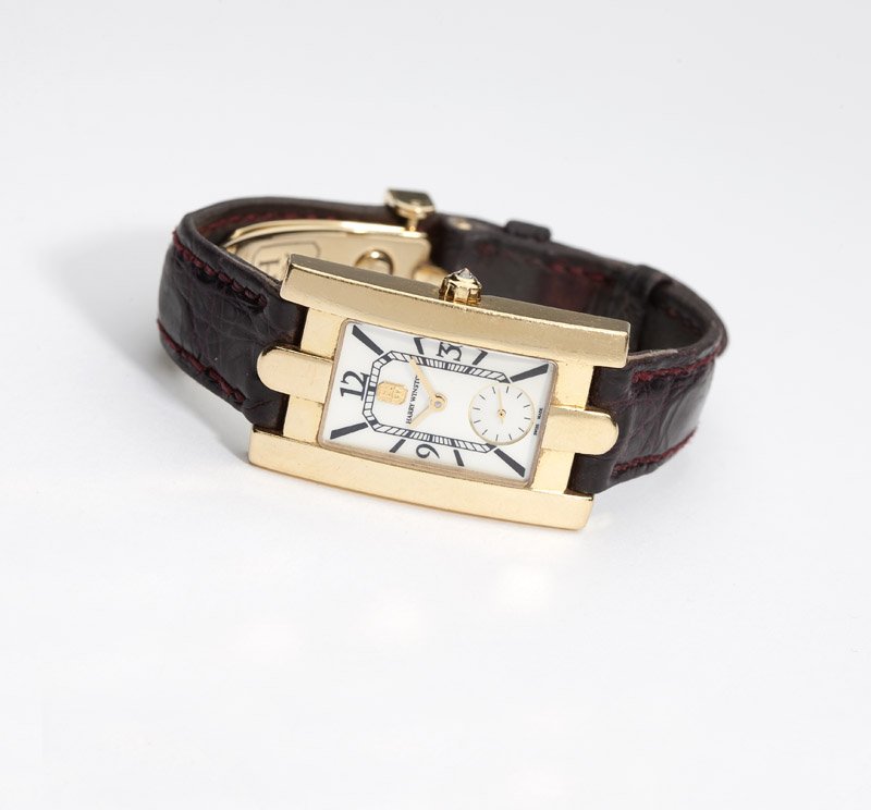 An 18K gold wristwatch, Harry Winston: A rectangular mother-of-pearl dial with black enamel Arabic and baton hour markers, sub seconds, dial reads 'Harry Winston' and applied gold tone 'HW' trade mark emblem, gold tone hands, attached to a