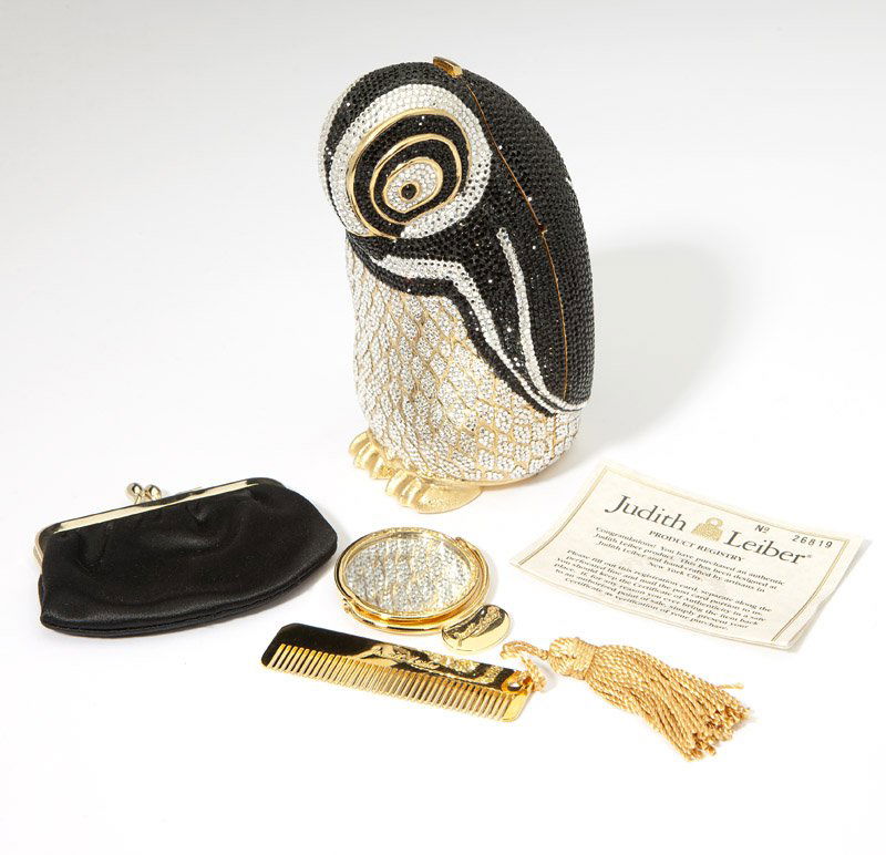 A crystal penguin minaudiere, Judith Leiber: Each item signed Judith Leiber; silver and black minaudiere comes with chain, black satin coinpurse, mirror, and comb still in tissue; accompanied with a signed pouch, dustbag, and one registration ca