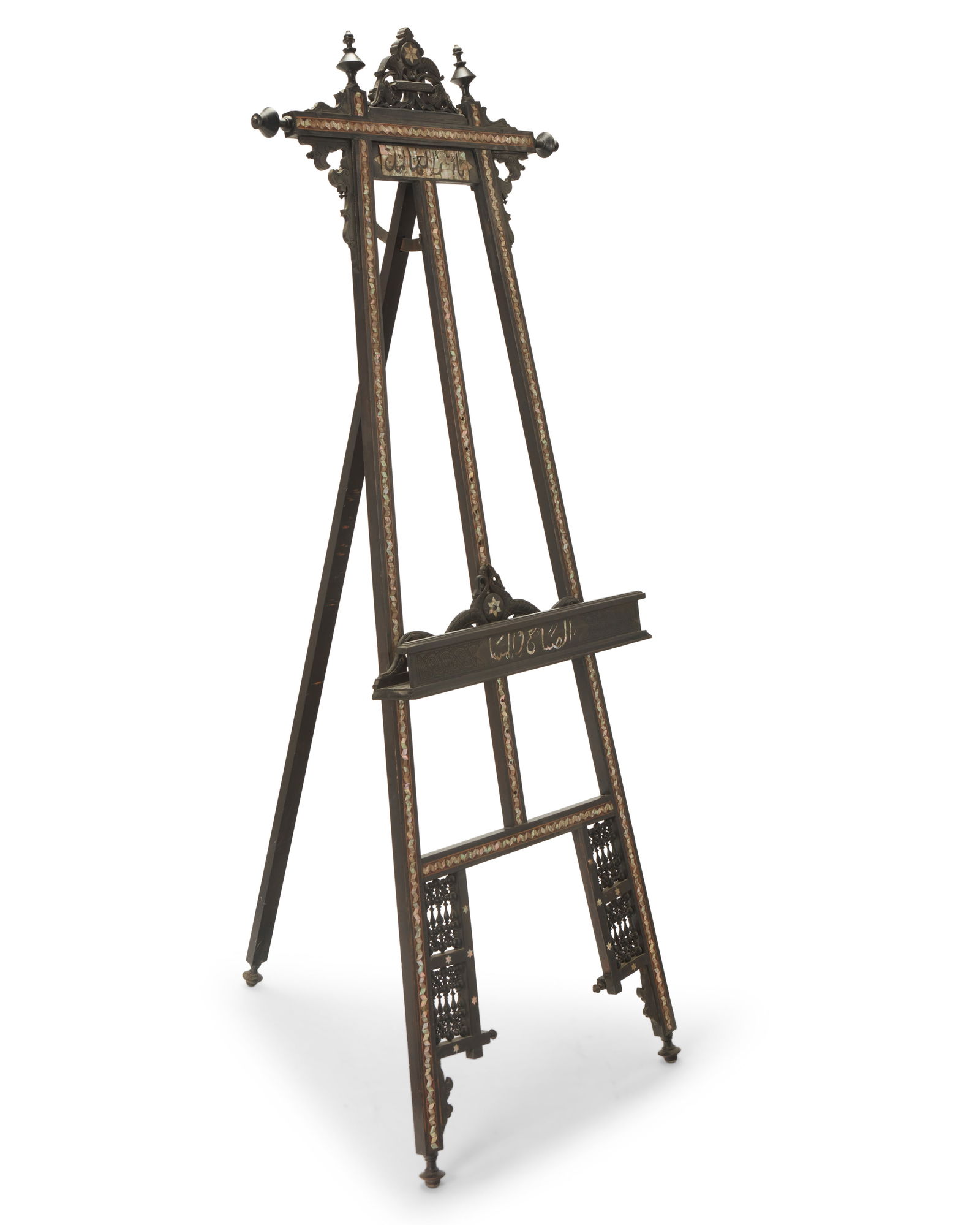A North African mother of pearl inlaid easel: A North African mother of pearl inlaid easelLate 19th/early 20th centuryInscribed in Arabic to canvas support and below mast: Morning and NightThe ebonized wood easel with openwork turned spindles and