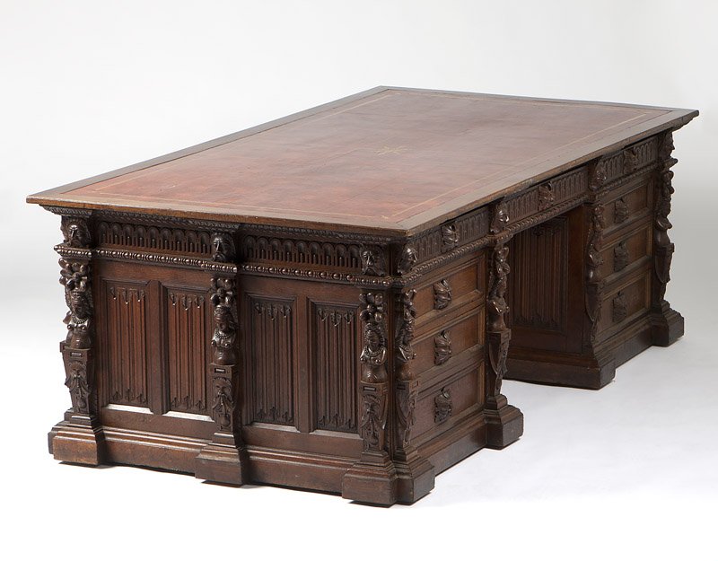 A Renaissance Revival carved oak partner's desk: Late 19th / early 20th century, with rectangular top with an inset gilt-tooled red leather writing surface above three frieze drawers and three further drawers to each pedestal, opposed by three friez