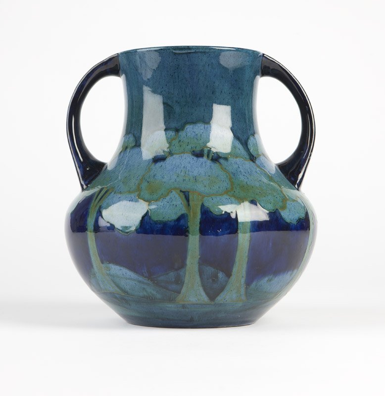A Moorcroft 'Moonlit Blue' double-handled vase: Circa 1925, impressed ''Moorcroft'' and ''Made in England'', further impressed ''5'' and ''D'', signed in green ''W. Moorcroft'', the squat body tubelined with stylized tall trees in a hilly landscape
