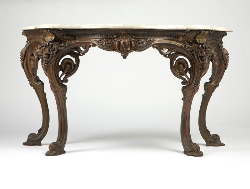 A Victorian cast iron console table: Dated 1854, impressed to underside of each of the three sections of frame with diamond frame English registry marks, the serpentine white marble top over a shell and foliate scroll-cast frieze raised