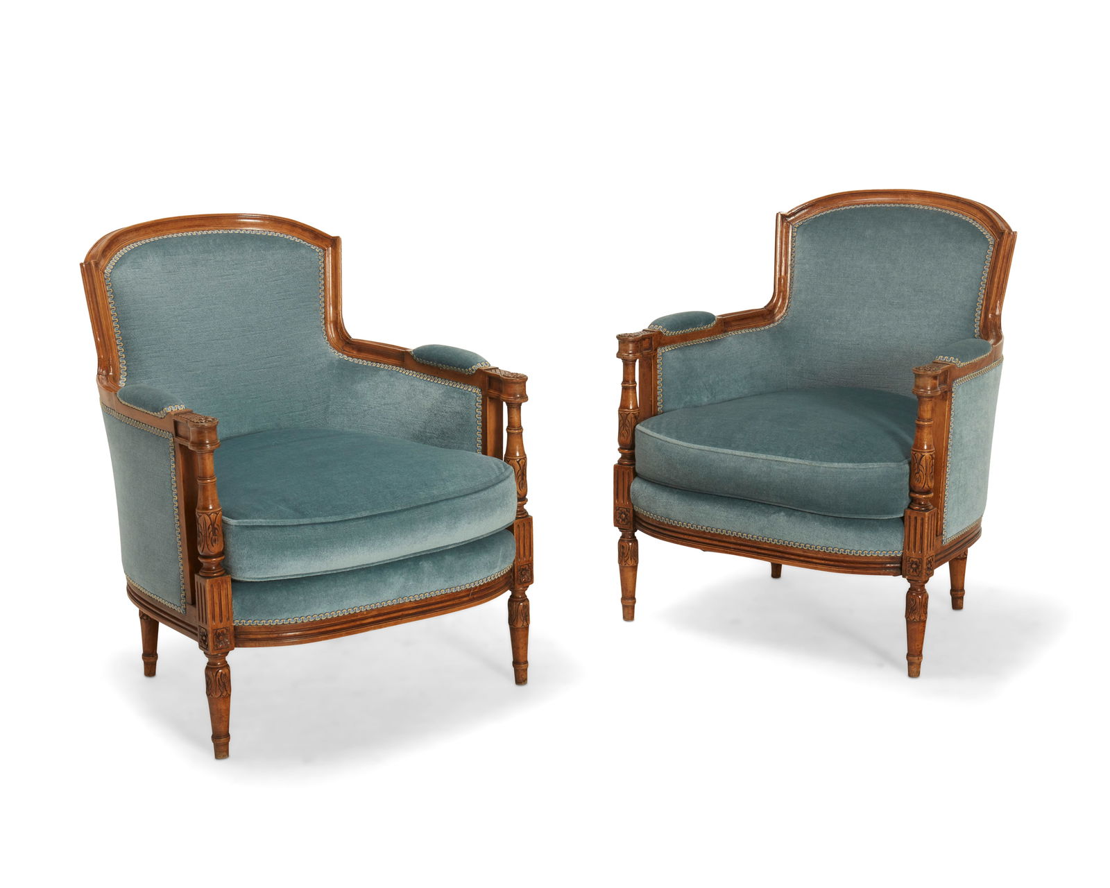 A pair of Louis XVI-style carved wood bergeres: A pair of Louis XVI-style carved wood bergeresEarly 20th centuryEach with carved acanthus and floral medallion accents to support fronts and armrest terminals, upholstered in a light blue velvet fabri