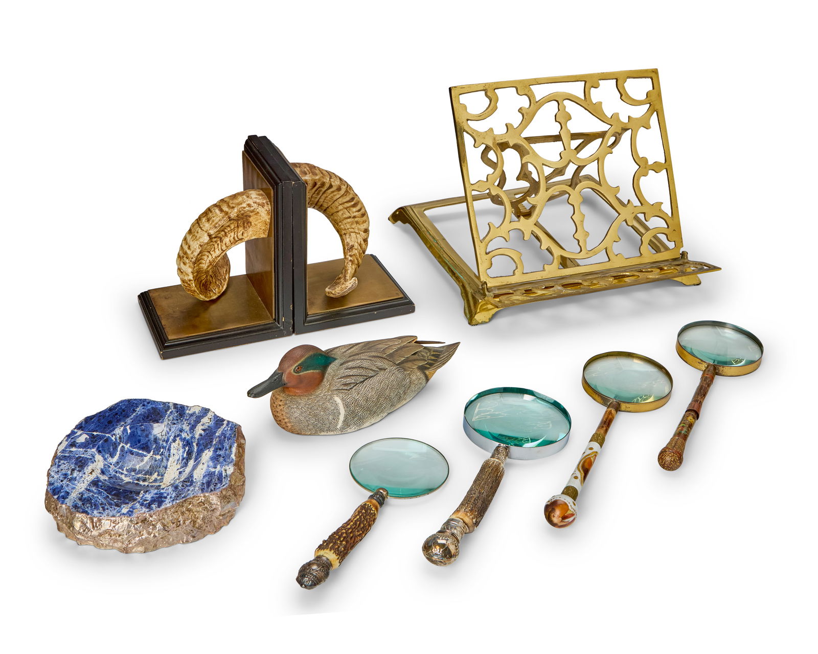 A group of book and desk accessories: A group of book and desk accessories20th centuryComprising an ANNA New York sodalite and silver bowl (1.5" H x 8" Dia.), a pair of composite, brass, and wood bookends in the form of ram's horns (Each: