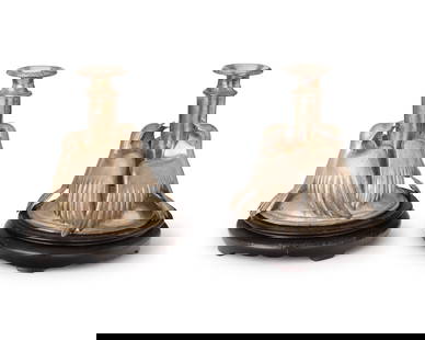 A pair of silver-plated figural candlesticks: A pair of silver-plated figural candlesticks20th centuryEach turned standard with two applied bird figures, set on a wood stand2 piecesEach overall: 7.75" H x 6.75" Dia.