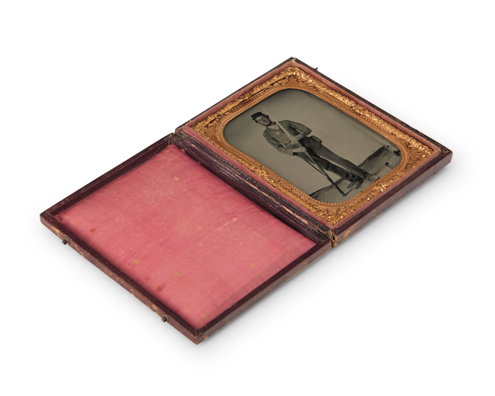 A Civil War era tintype: A Civil War era tintypeA tintype depicting a soldier with his rifle and bayonet, with a chased gold-toned metal preserver within a red velvet-lined tooled leather caseSight: 3.5" H x 2.5" W
