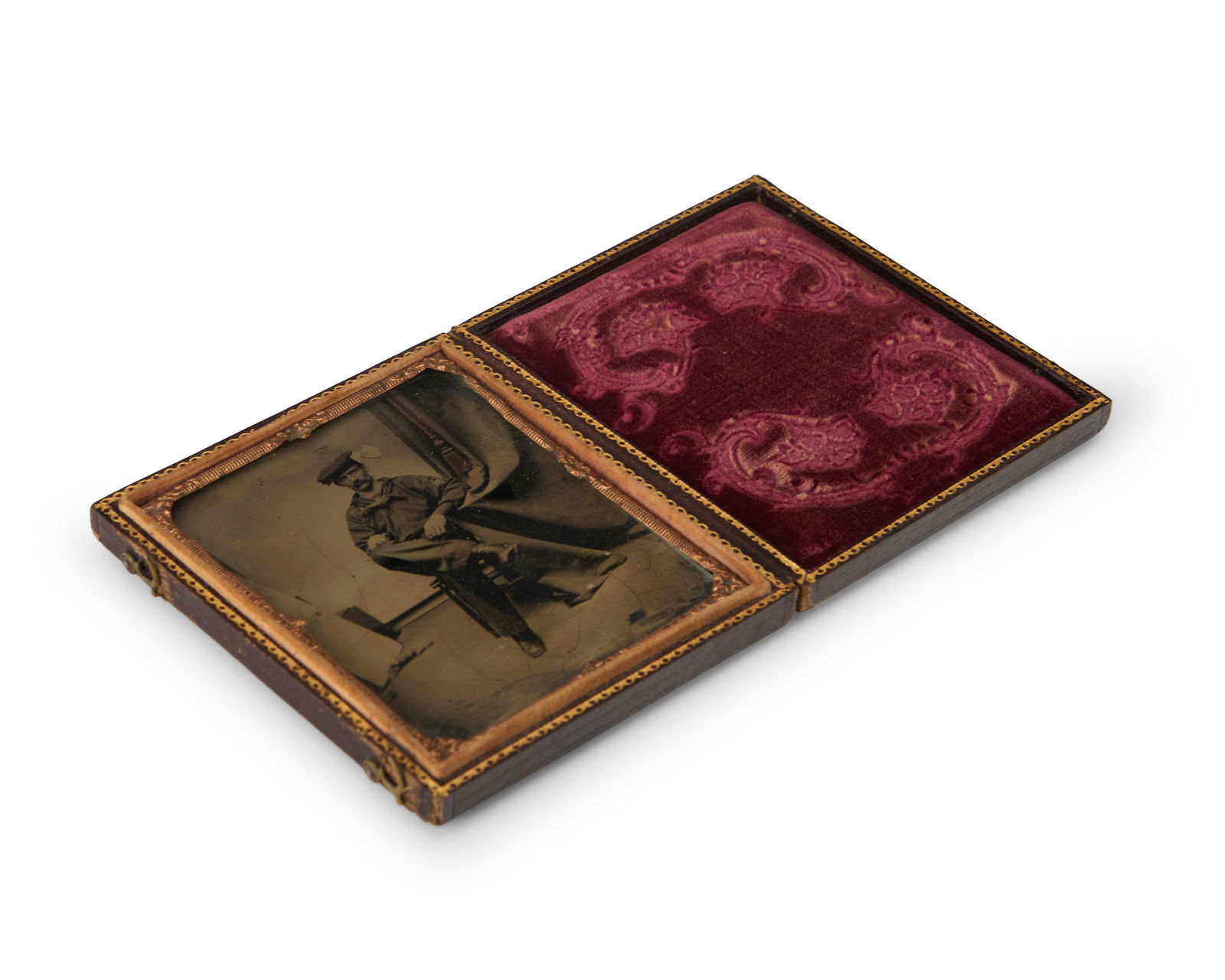 A 19th century tintype of a seated man: A 19th century tintype of a seated manA tintype depicting a seated man with a curtain to his left, with a chased gold-toned metal preserver within a magenta velvet-lined tooled leather caseSight: 3" H